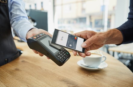 Ein Kunde bezahlt einen Kaffee mit seinem Smartphone über Google Pay