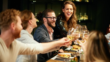 Freunde essen, trinken und lachen gemeinsam am Tisch in einem Restaurant