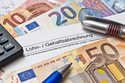 Euroscheine und Zettel mit Inschrift „Gehaltsabrechnung“