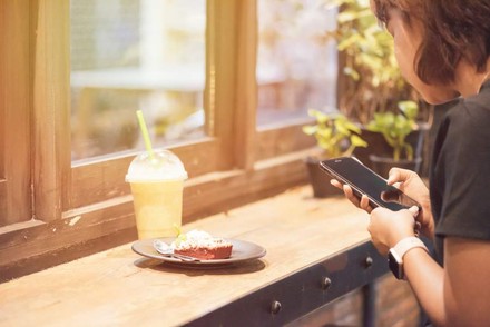 Frau mit Smartphone vor Dessert