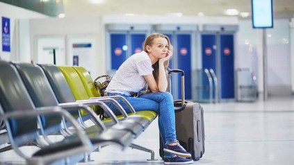 Eine Frau wartet alleine in einer Wartehalle am Flughafen