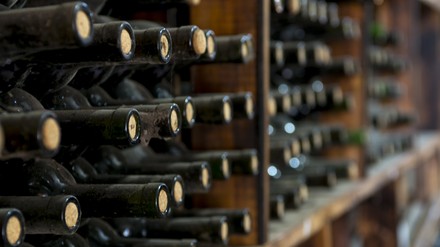 Nahaufnahme staubiger, gelagerter Weinflaschen in einem Weinkeller