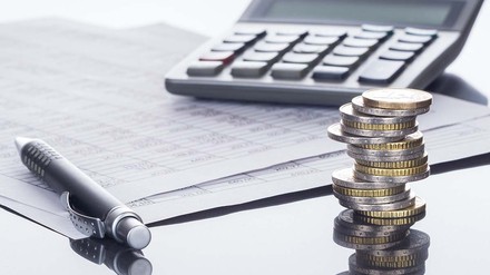 Papiere, Taschenrechner, Stift und ein Stapel Euro-Münzen