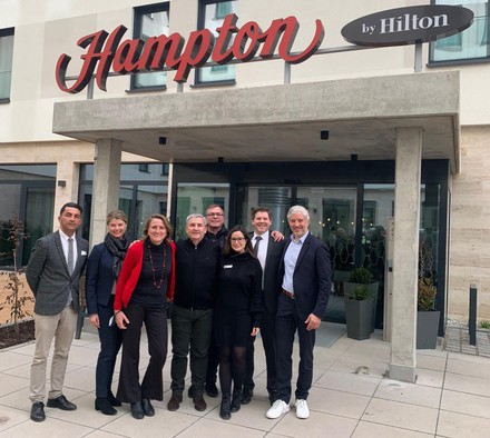 Gruppenfoto des Projektteams des Hampton by Hilton Munich North vor dem Eingang des Hotels bei der Eröffnung