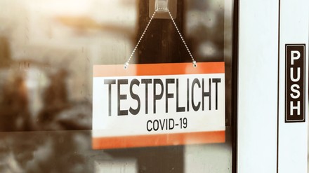 Testpflicht, translated: – mandatory testing sign hangs on the door of a store