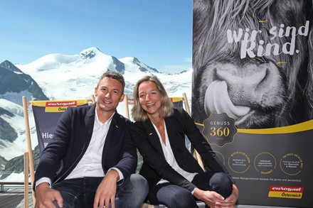 Zwei lächelnde Geschäftsleute sitzen auf einer Terrasse inmitten verschneiter Berge