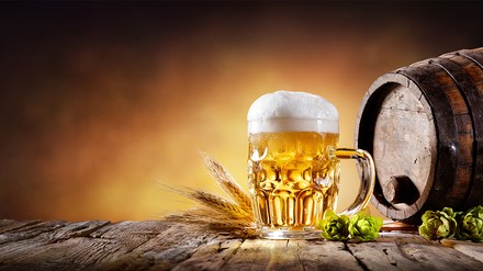 Gefüllter Bierkrug neben einem kleinen Fass