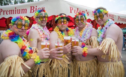 Englische Touristen mit Baströcken und bunten Blumenketten beim Trinken des Zywiec Bieres