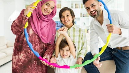Eine fröhliche arabische Familien hält einen Hula-Hoop-Reifen aus verschiedenen Farben