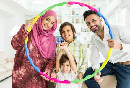 Eine fröhliche arabische Familien hält einen Hula-Hoop-Reifen aus verschiedenen Farben