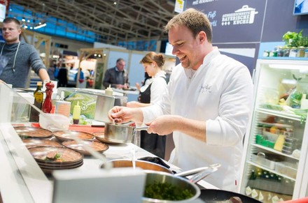 An einem Messestand auf der Food & Life bereitet ein Koch ein Gericht zu