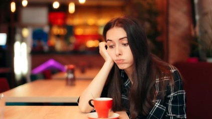 Eine Frau starrt genervt auf eine leere Tasse