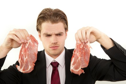 Mann betrachtet misstrauisch Fleisch in seiner Hand