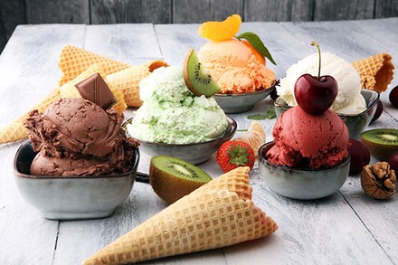 Diverse Eissorten in Schüsseln mit Obst und Waffeln