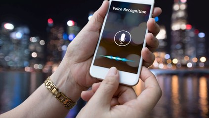 Zwei Hände halten ein Smartphone mit aktivierter Spracherkennung
