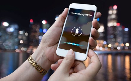 Zwei Hände halten ein Smartphone mit aktivierter Spracherkennung
