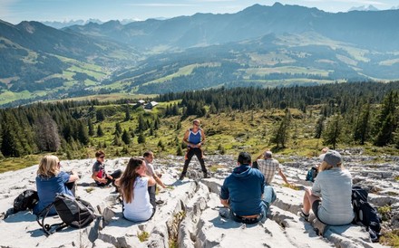 Einige Bergwanderer vor einem Bergpanorama bei einer Besprechung mit dem Wanderführer