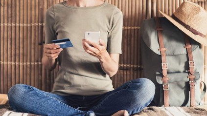 Eine Frau auf Reisen mit ihrer Kreditkarte und ihrem Smartphone in der Hand