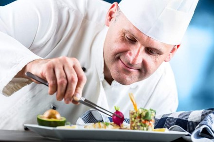 Ein lächelnder Koch bereitet feine Köstlichkeiten zu