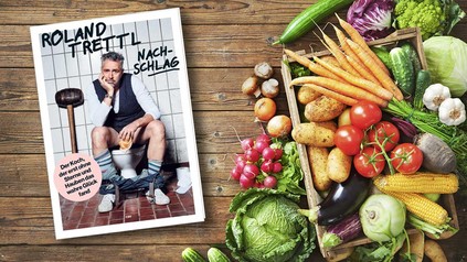 Buchcover "Nachschlag" von Roland Trettl liegt auf einem Tisch mit verschiedenen Gemüsesorten