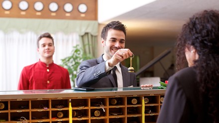 Mann bei der Schlüsselübergabe an der Rezeption eines Hotels