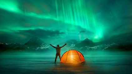 Ein Mann steht vor einem Zelt und betrachtet das Nordlicht
