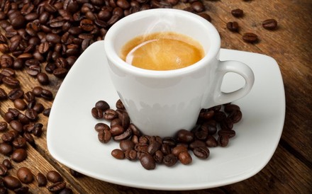 Eine Tasse gefüllt mit Espresso und Kaffeebohnen drumherum