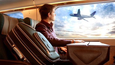 Ein Mann beobachtet vom Zug aus ein Flugzeug