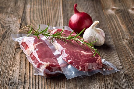 Vakuumiertes Fleisch mit Zwiebeln und einer Stange Rosmarin