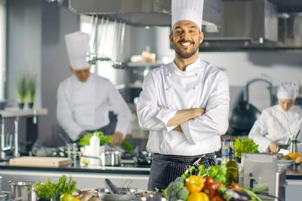 Ein grinsender Koch mit Gemüse in der Küche