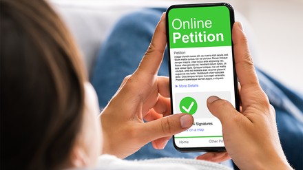 Mann hält Handy in der Hand, auf dem eine Online Petition geöffnet ist