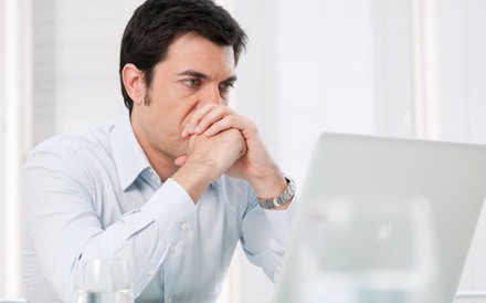 Ein Mann blickt nachdenklich auf einen Laptop