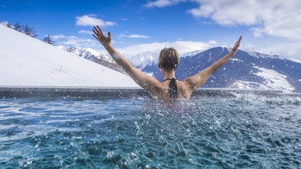 Frau in Pool streckt Arme in die Luft
