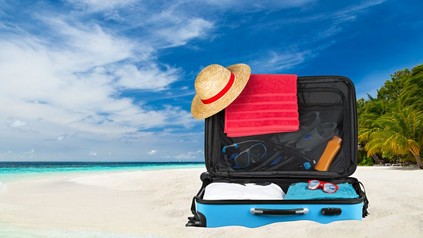 Ein vollgepackter Koffer am Strand