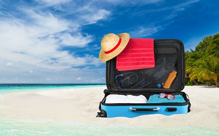 Ein vollgepackter Koffer am Strand