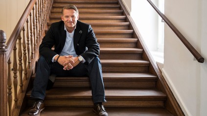 Alexander Fitz sitzt lächelnd auf einer Treppe