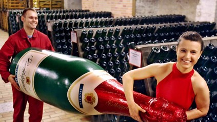 Zwei rot gekleidete Personen tragen eine riesige Rotkäppchenflasche