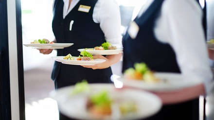 Zwei Servicekräfte, die fünf Teller tragen