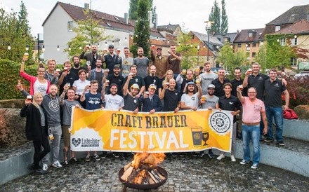 Eine Gruppe fröhlicher Menschen mit einem Banner des Craft Brauer Festivals