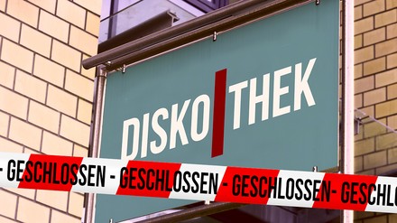 Schild mit dem Schriftzug „Diskothek“ und ein rot-weißes Absperrband auf dem „geschlossen“ steht