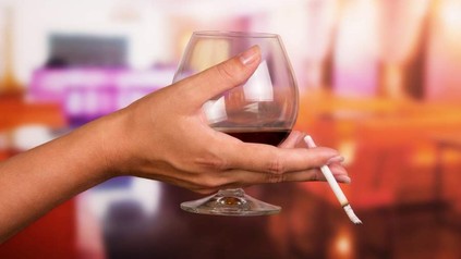 Eine Hand, die ein Glas Wein und eine Zigarette hält