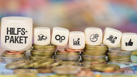 Würfel mit der Aufschrift Hilfspaket und Euro-Münzen