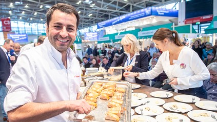 Spitzenkoch Ali Güngörmüs an einem Messestand