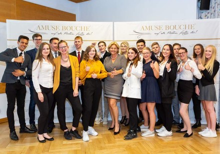 Eine Gruppe junger Lehrlinge vor einem Amuse-Bouche Plakat