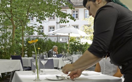 Eine Servicekraft deckt auf einer Terrasse einen Tisch