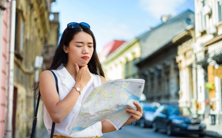 Nachdenkliche asiatische Touristin blickt auf eine Landkarte