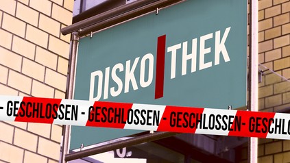 Diskothek-Schild und rot-weiß-gesteiftes Absperrband mit der Aufschrift "Geschlossen"