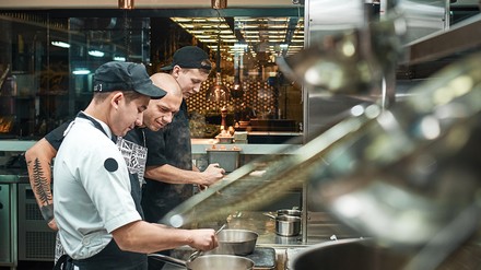 Kochausbilder in einer Küche mit zwei Auszubildenden