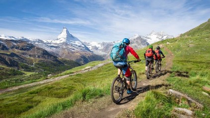 Drei Fahrradfahrer auf einem Weg in den Alpen.