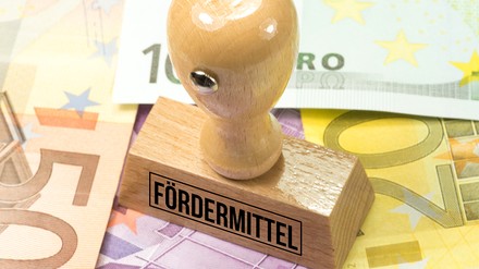 Stempel mit der Aufschrift „Fördermittel“ steht auf Euroscheinen